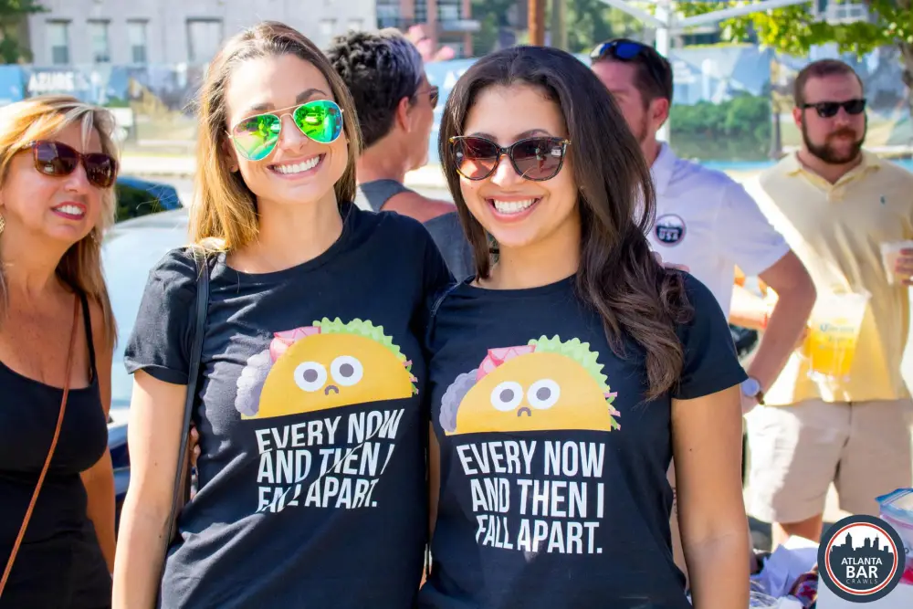 Two smiling women with sunglasses and Bar Crawl USA VIP taco shirts
